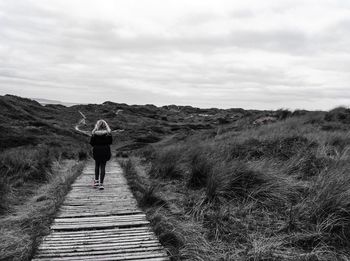 Rear view of woman walking on a wood track path. 