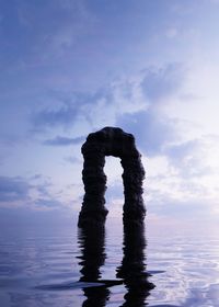 Silhouette rock in sea against sky