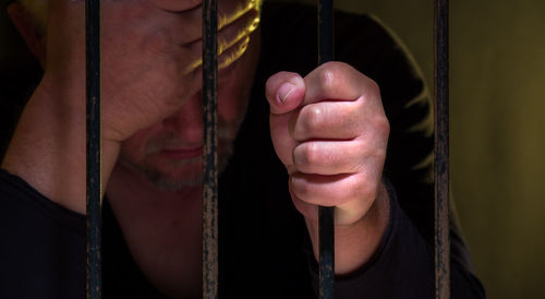 Prisoner with head in hand behind security bars