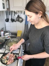 Midsection of woman standing in kitchen at home