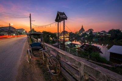 Cars on bridge in city against sky during sunset