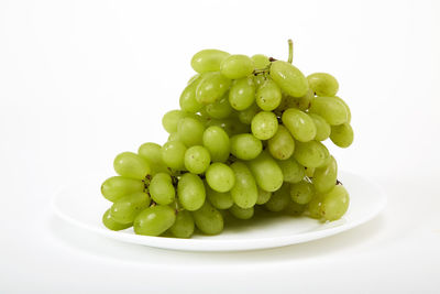 Close-up of grapes in bowl over white background