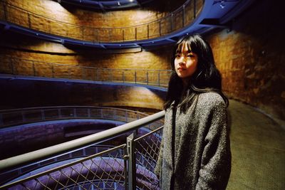 Portrait of woman standing against railing