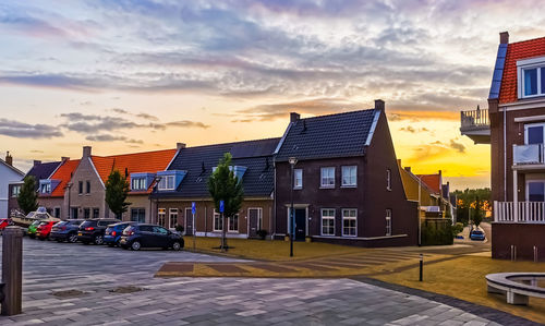 Street amidst buildings against sky during sunset