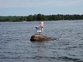 Commode in calm lake with trees in distance