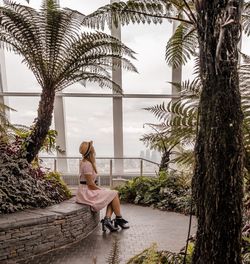 Woman sitting on palm tree trunk