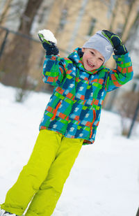 Portrait of boy throwing snow while standing in snow outdoors