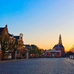 Street leading towards church against sky during sunset