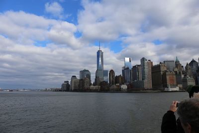 Sea by modern buildings against sky in city