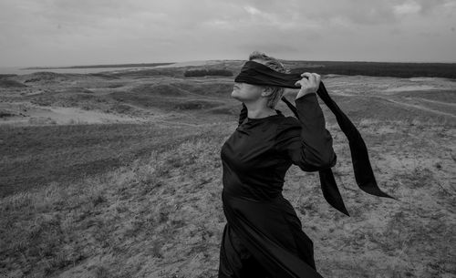 Woman covering eyes with scarf while standing on land