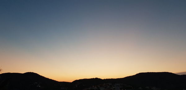 Silhouette mountains against clear sky during sunset