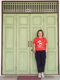 Portrait of smiling man standing against closed door