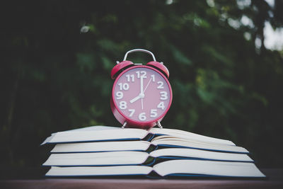 Close-up of clock on book against tree