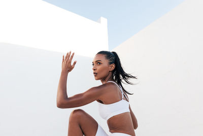 Portrait of young woman standing against white background