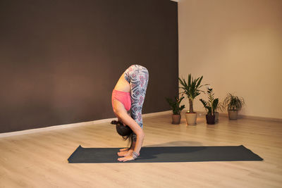 Young woman doing yoga on yoga mat in atmospheric yoga studio