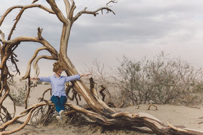 Woman sitting by dead tree