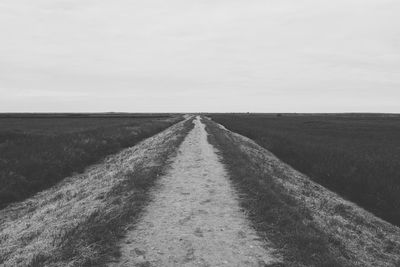 Road amidst agricultural field against sky