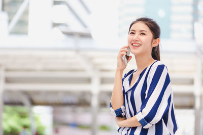 Beautiful young woman using phone while standing outdoors