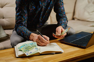 Midsection of woman using laptop on table