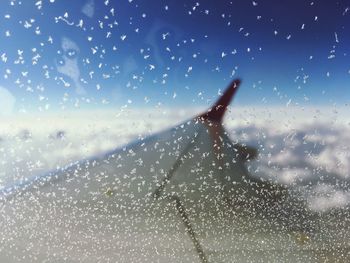 Cropped image of airplane wing seen through window during winter
