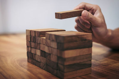 Cropped image of man stacking dominoes on table