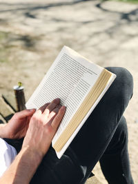 Midsection of man reading book at park