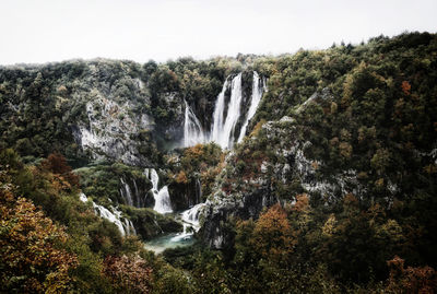 Scenic view of waterfall in forest against clear sky