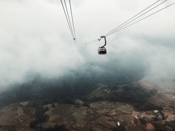 Overhead cable car against cloudy sky