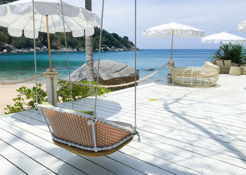 Chairs by swimming pool at beach against sky