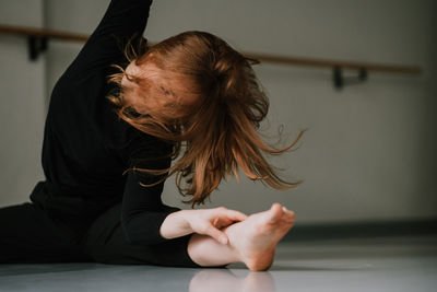 Young woman dancing against wall