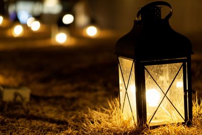Close-up of illuminated lantern on field at night