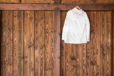 Shirt on coathanger against wooden wall at home