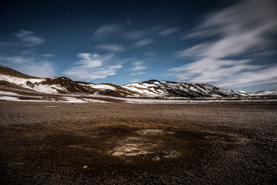 Scenic view of volcanic landscape and snowcapped mountains against night sky