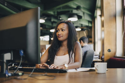 Young businesswoman using computer at desk in creative office