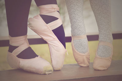 Low section of woman and girl wearing ballet shoes