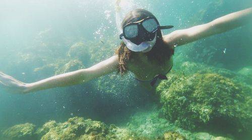 Woman snorkeling by coral undersea