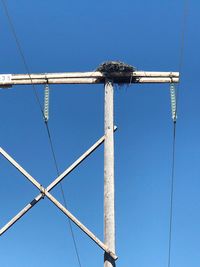 Low angle view of telephone pole against clear blue sky