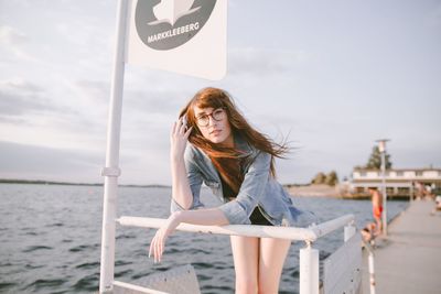 Woman standing by railing against sea