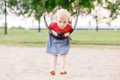 Full length portrait of cute girl swinging at park