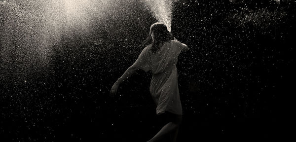 Woman spraying water through gardening hose