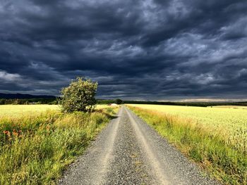 Road amidst field against sky