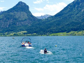Man wakeboarding in lake by mountains against sky