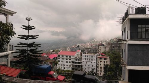 Buildings in town against cloudy sky