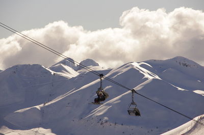 Scenic view of snow covered mountains against sky, with a ski lift in front