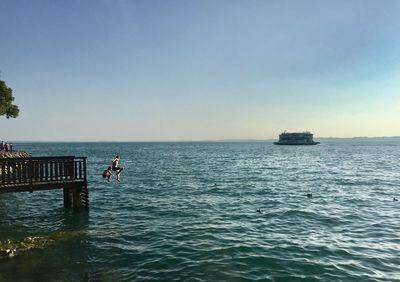 People diving in sea against blue sky