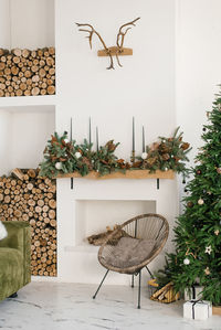 Rustic home interior of the living room with a christmas wreath, fireplace, firewood, armchair 