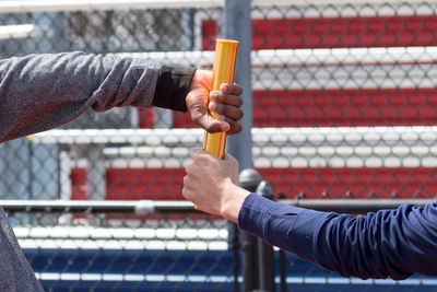 Close-up of man holding metal fence