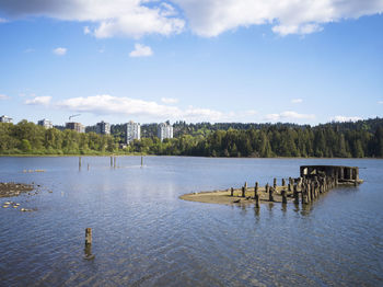 Wooden posts in lake against sky