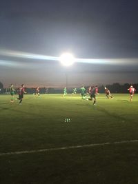 People playing soccer on field against sky