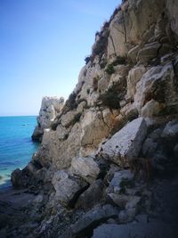 Rock formation in sea against clear sky